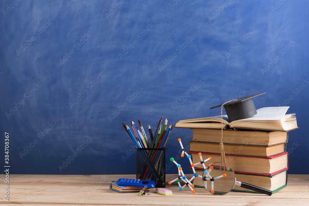 Education and sciences concept - books on the teacher desk in the auditorium, chalkboard on the back