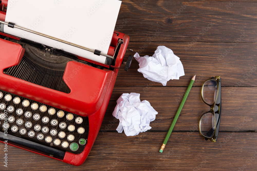 Writer or journalist workplace - vintage red typewriter, glasess and notepad on the wooden desk