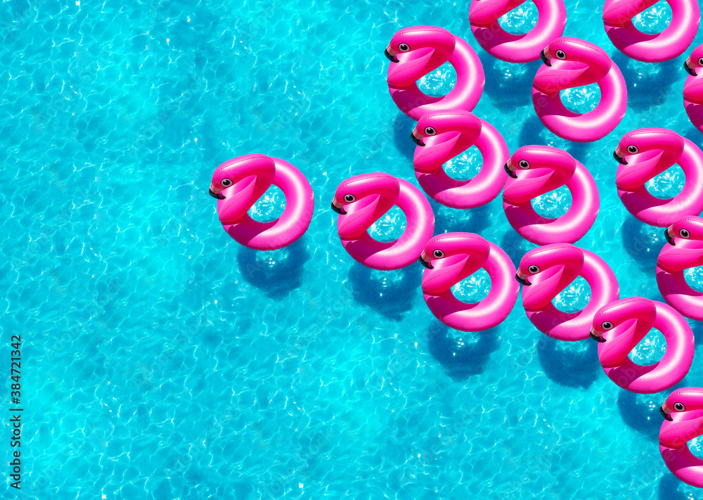 Large group of inflatable flamingo buoy swim in the swimming pool view from above