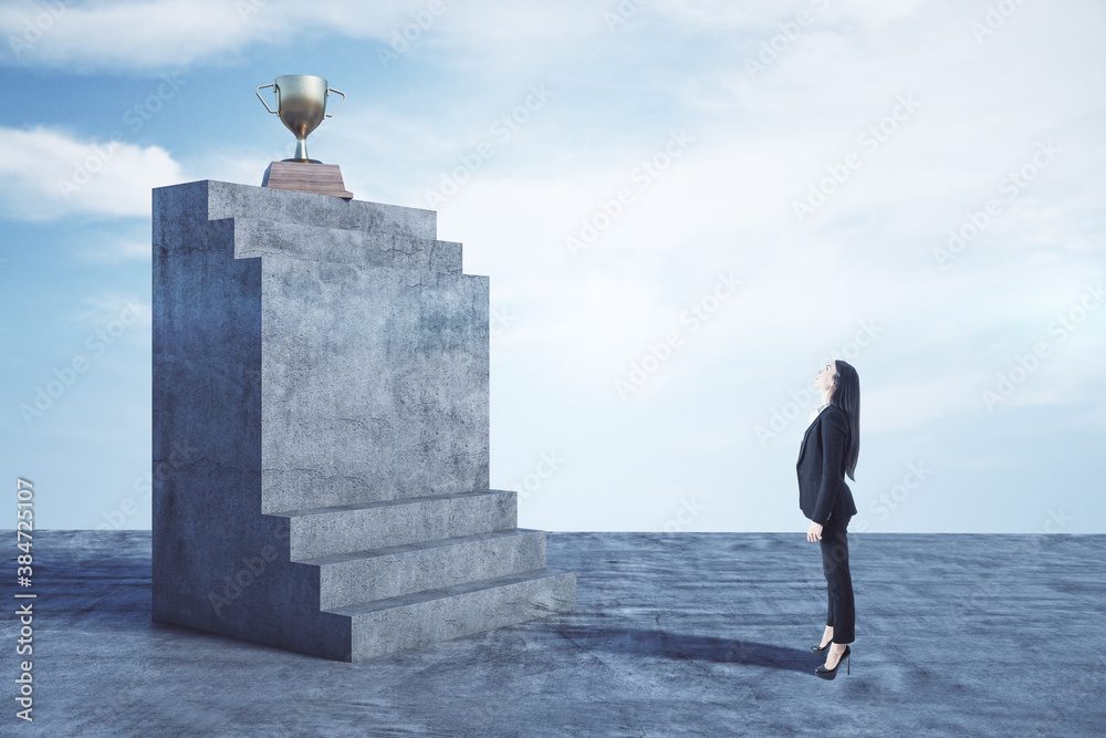 Businesswoman in suit looking on concrete stairs with golden winners cup