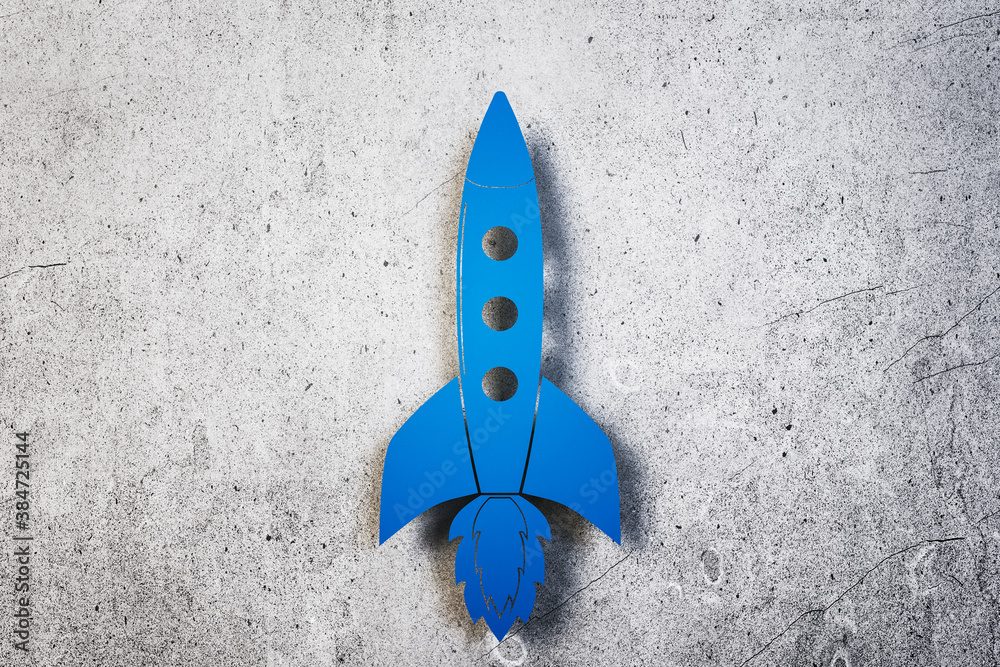 Toy blue rocket on concrete wall background.