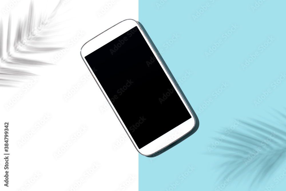 Smartphone with tropical palm leaves and shadow - flat lay