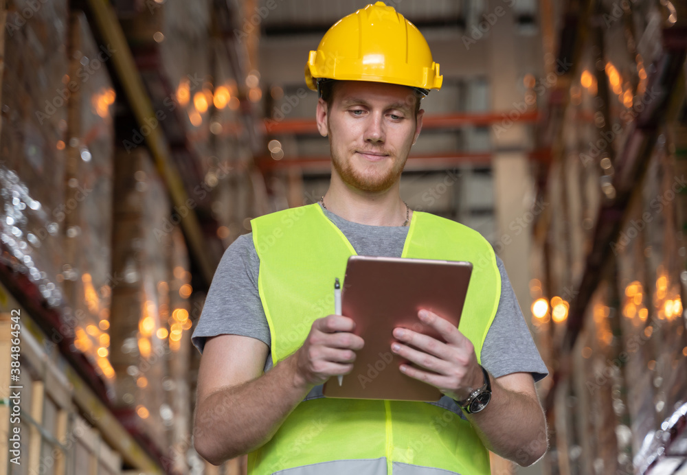 Man looking at check sheet to checking inventory by lablet. A young caucasian man wearing helmet and