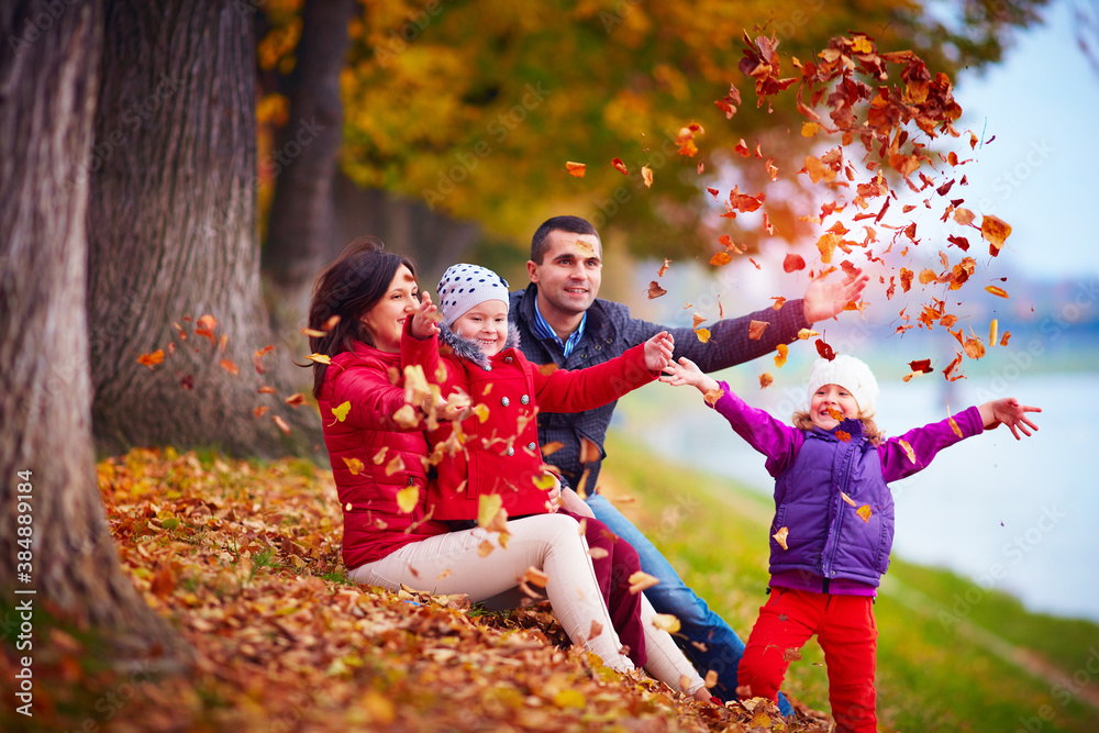 happy family playing among fallen leaves in autumn park