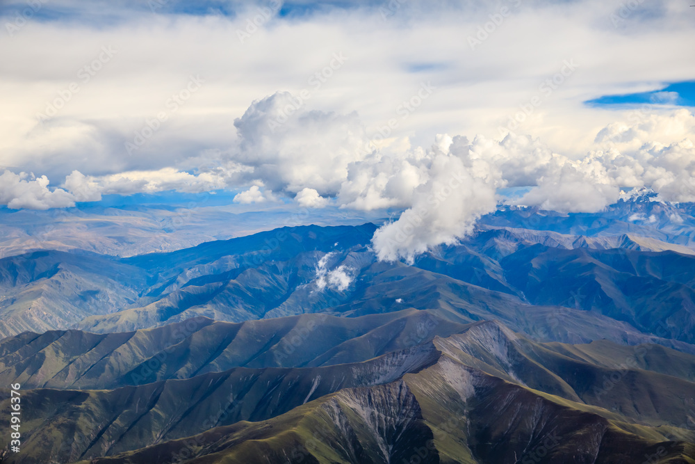 Aerial view above the clouds and mountain peaks on a sunny day.