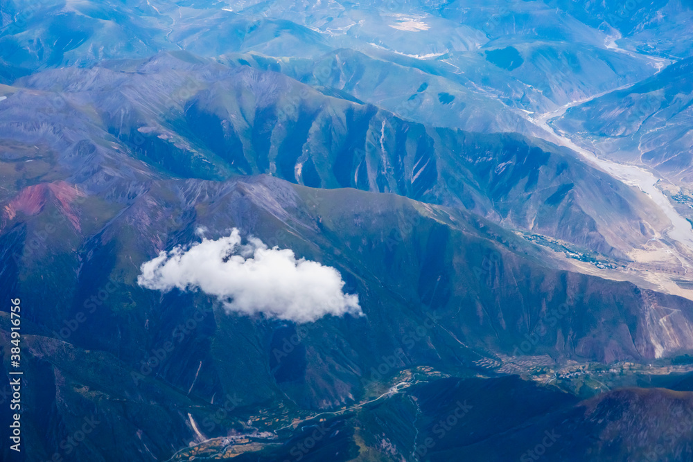 在阳光明媚的日子里俯瞰云朵和山峰。从飞机上俯瞰山景。