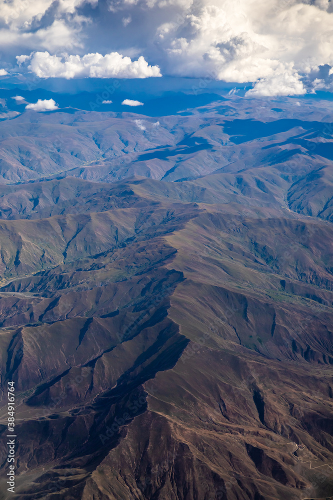 Aerial view above the clouds and mountain peaks on a sunny day.