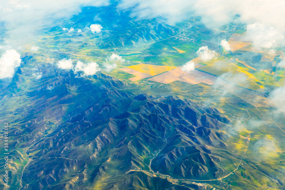 阳光明媚的日子里，云层和山峰上方的鸟瞰图。飞机上的山景。