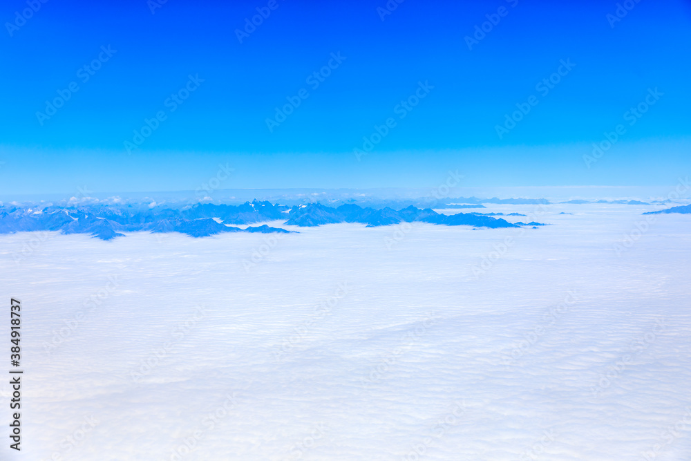 在阳光明媚的日子里俯瞰云朵和山峰。从飞机上俯瞰山景。