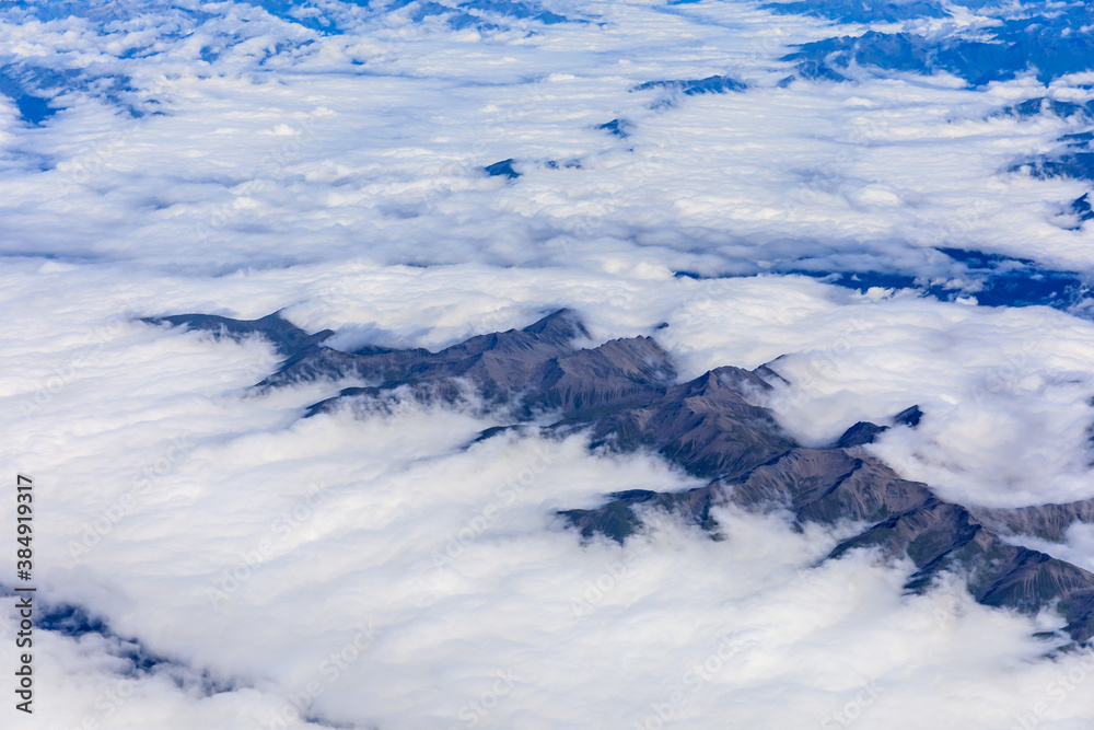 Aerial view above the clouds and mountain peaks on a sunny day.mountain view from airplane.