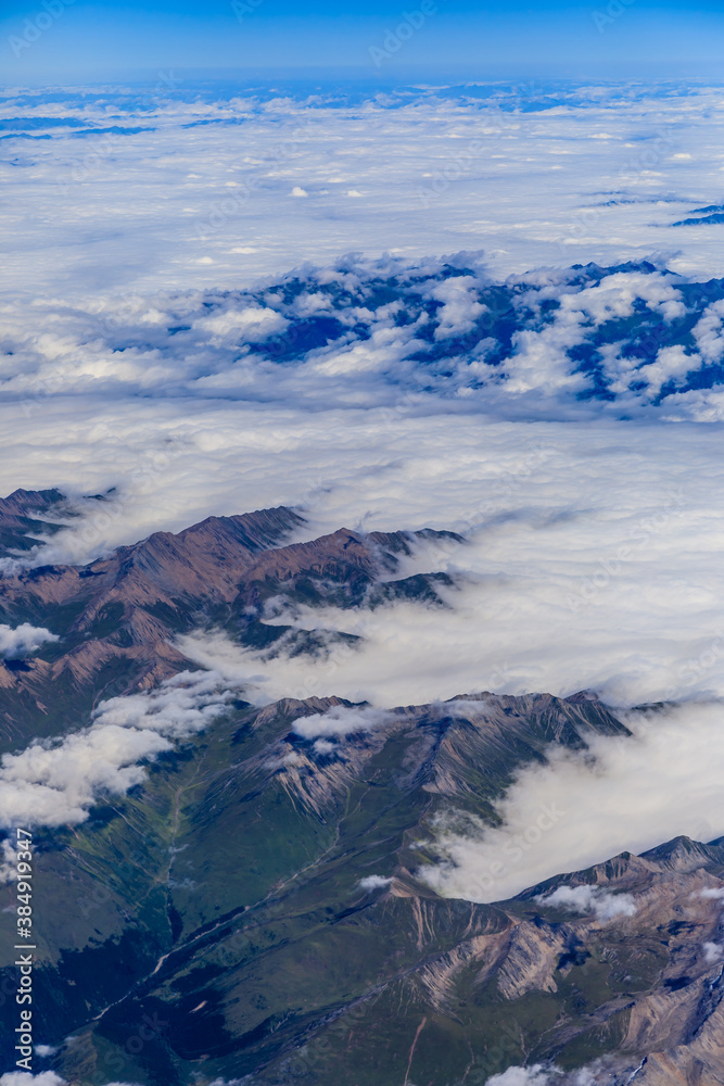 Aerial view above the clouds and mountain peaks on a sunny day.mountain view from airplane.