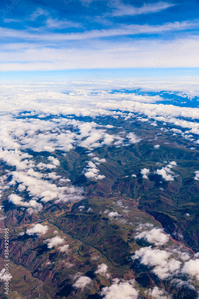 Aerial view above the clouds and mountain peaks on a sunny day.