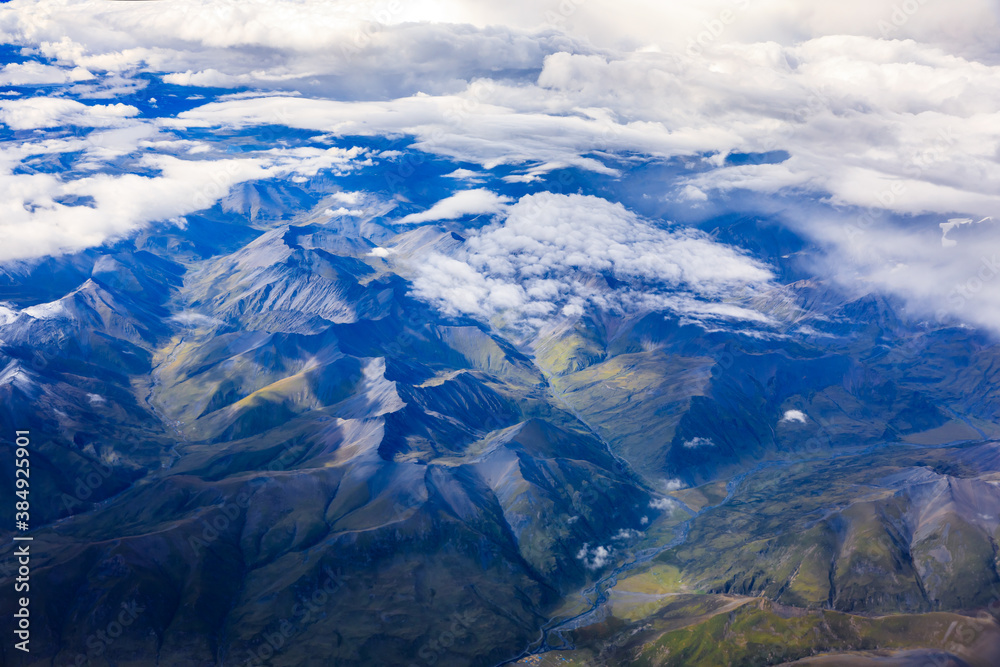 Aerial view above the clouds and mountain peaks on a sunny day.