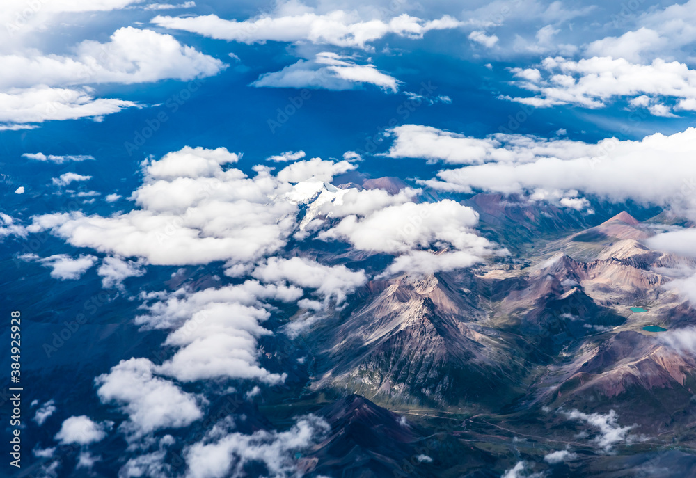 Aerial view above the clouds and mountain peaks on a sunny day.