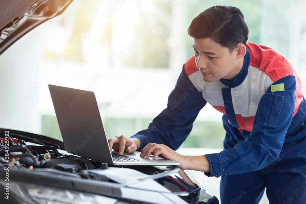  Asian technician or Auto mechanic check engine system. new car with a notebook computer in car serv