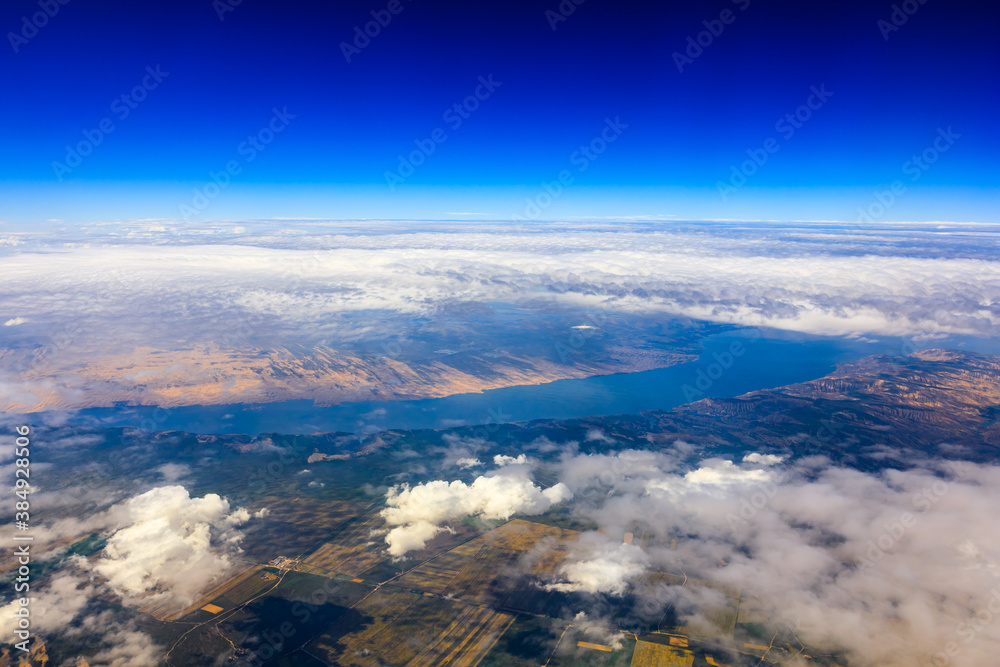 阳光明媚的日子里，云层和山峰上方的鸟瞰图。飞机上的山景。