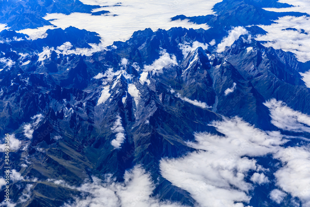 Aerial view above the clouds and mountain peaks on a sunny day.