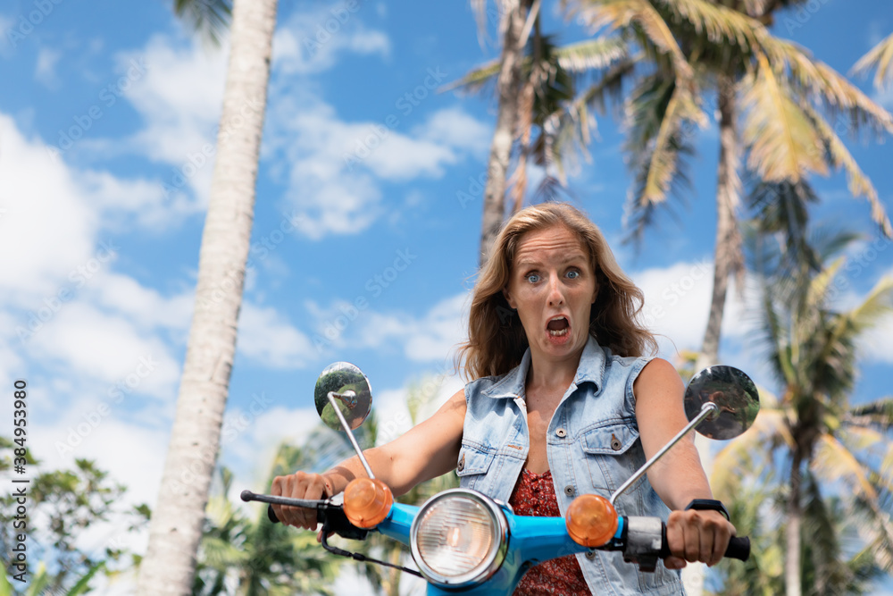 Face portrait of young frightened woman. Girl riding on rental motorbike without helmet . Risk of ro