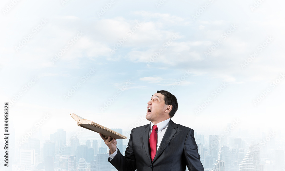 Surprised businessman holding open old book