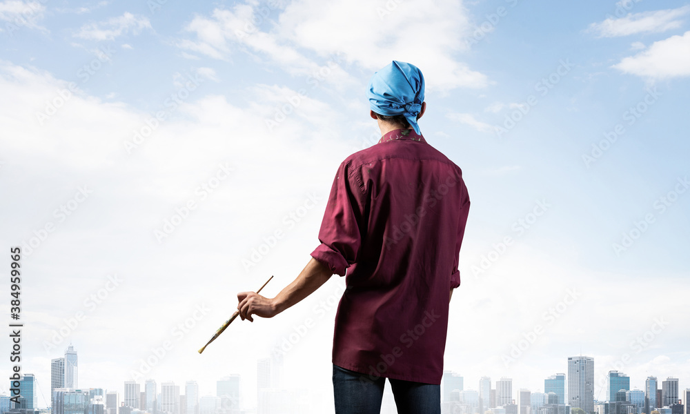 Young male artist holding paintbrush