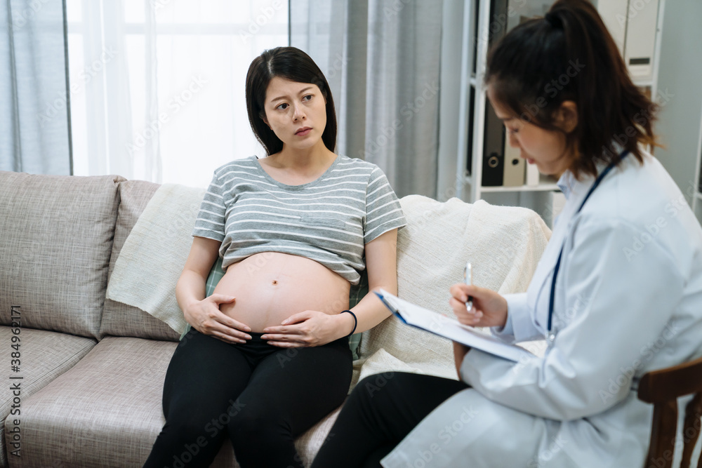 young asian korean pregnant woman sitting on sofa during psychotherapy. Worried maternity lady liste