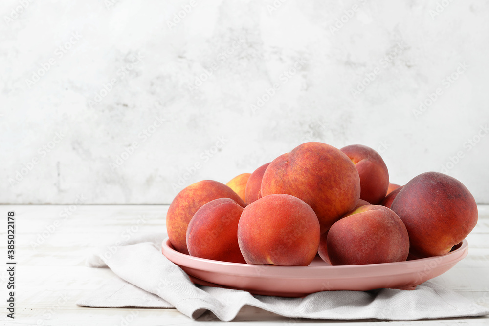 Plate with sweet peaches on table