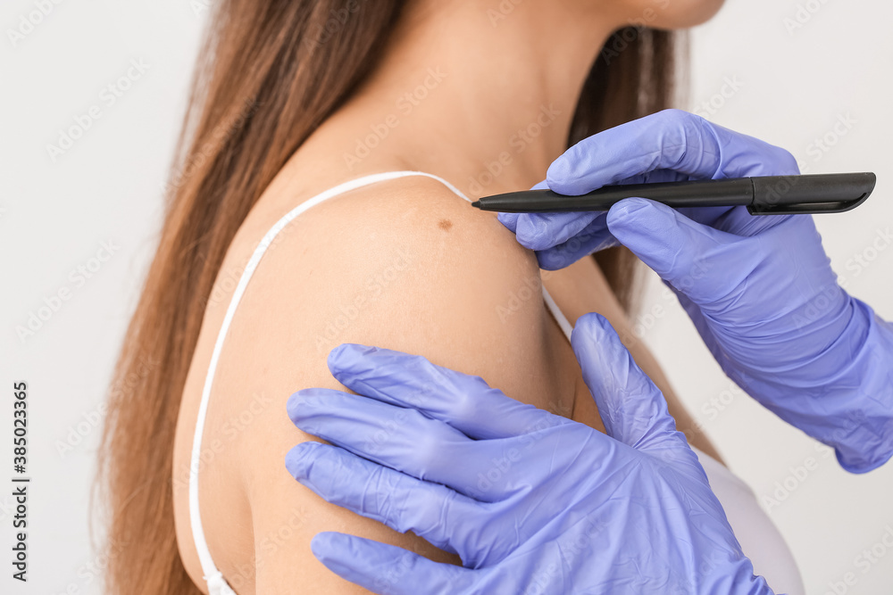 Dermatologist examining patient on light background, closeup