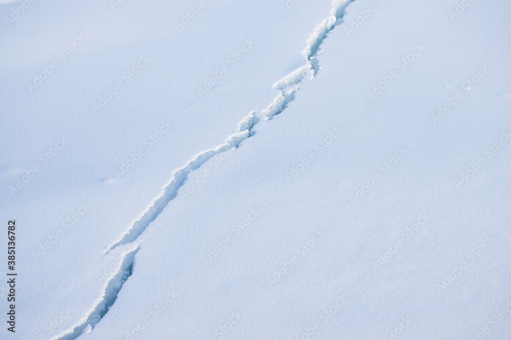 Crack in the ice cover. Snow covered ice. Cracked ice floes on the sea in the Arctic. Polar region. 