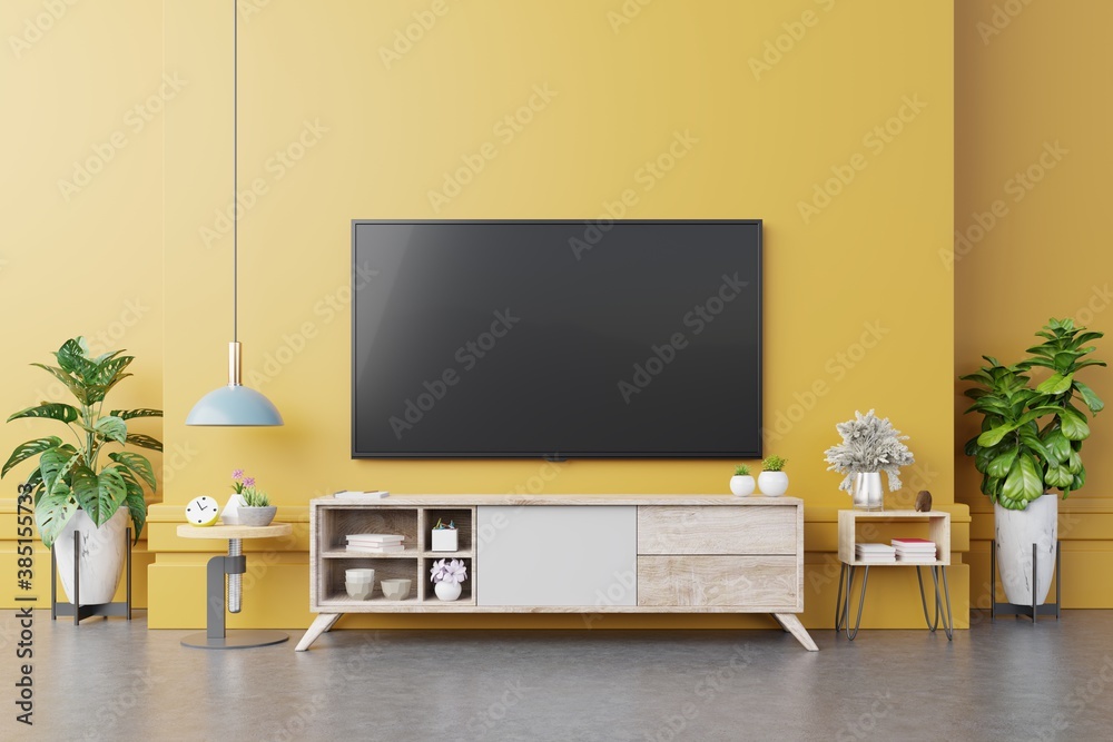 TV on cabinet in modern living room with lamp,table,flower and plant on yellow wall background.