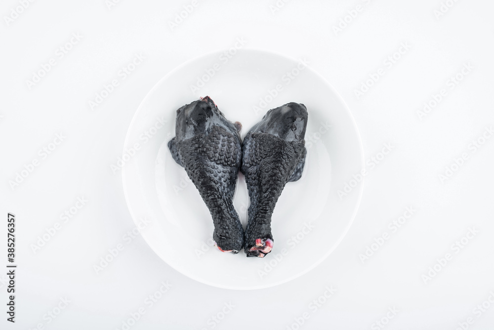 Two fresh black chicken drumsticks on white background