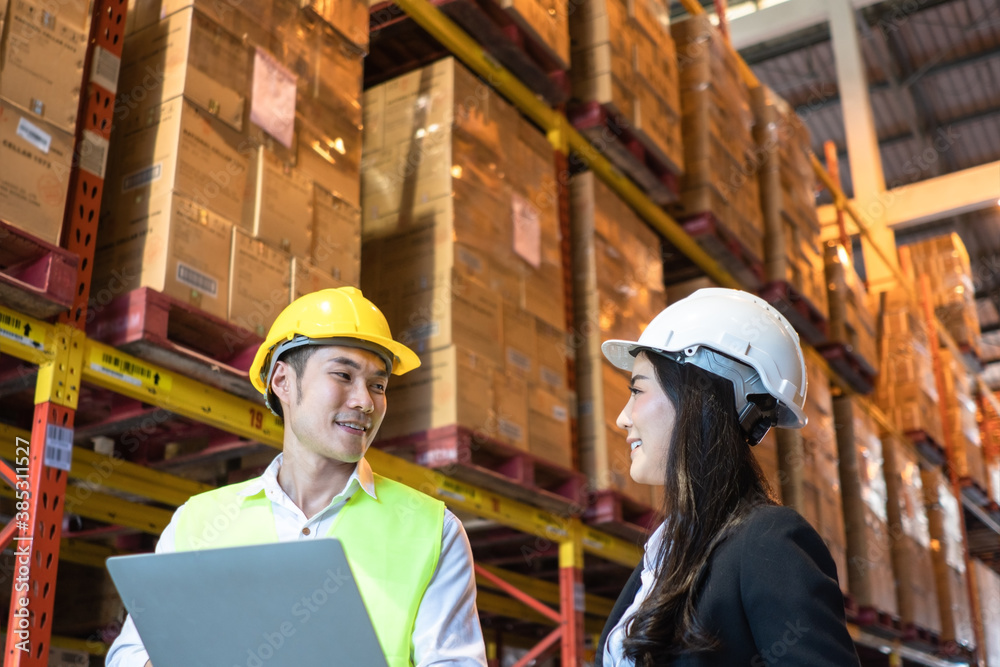 Asian happy male factory worker presenting work project from laptop to female company manager, looki