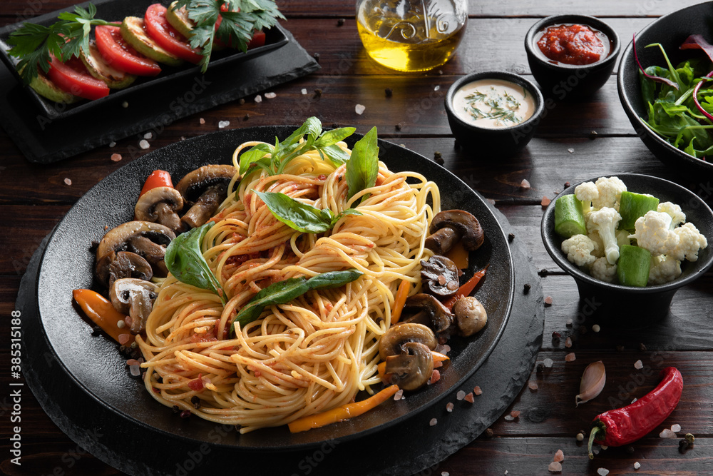 Pasta spaghetti with mushrooms and vegetables on black plate. Menu concept.