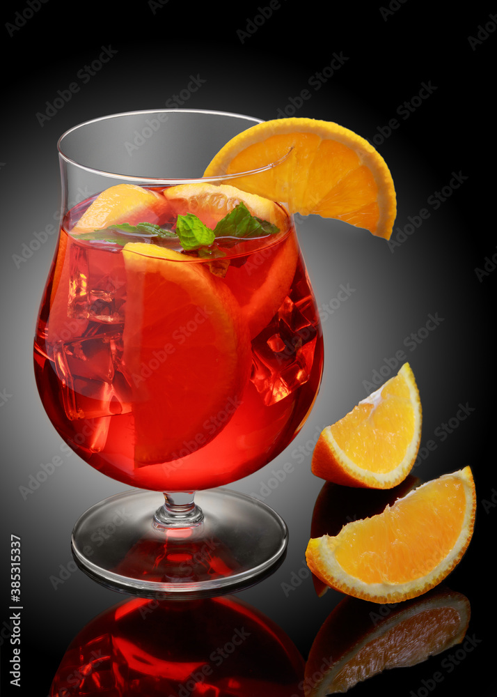 Glass of Aperol Spritz cocktail decorated with orange at black background.