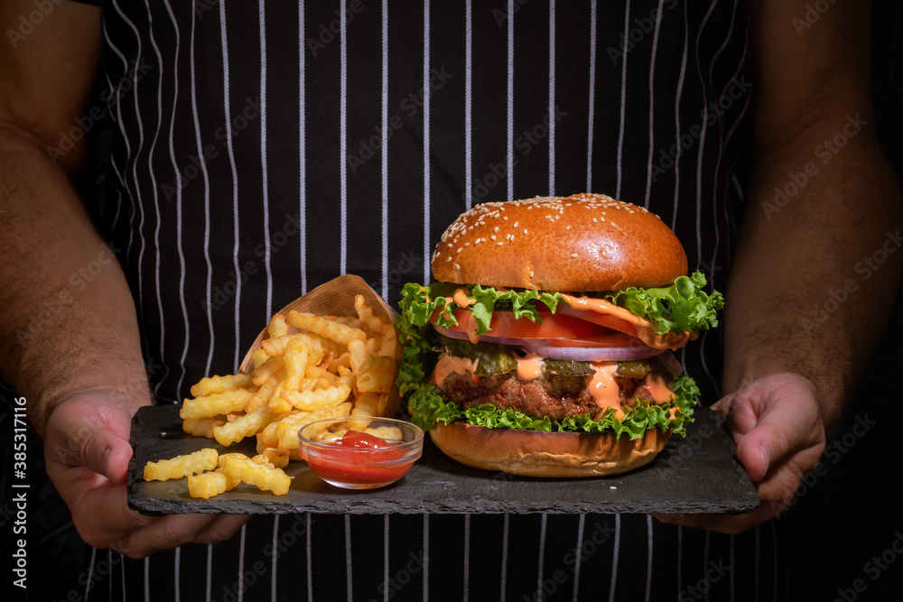 fresh tasty burger and french fries hold in hands .Close up.