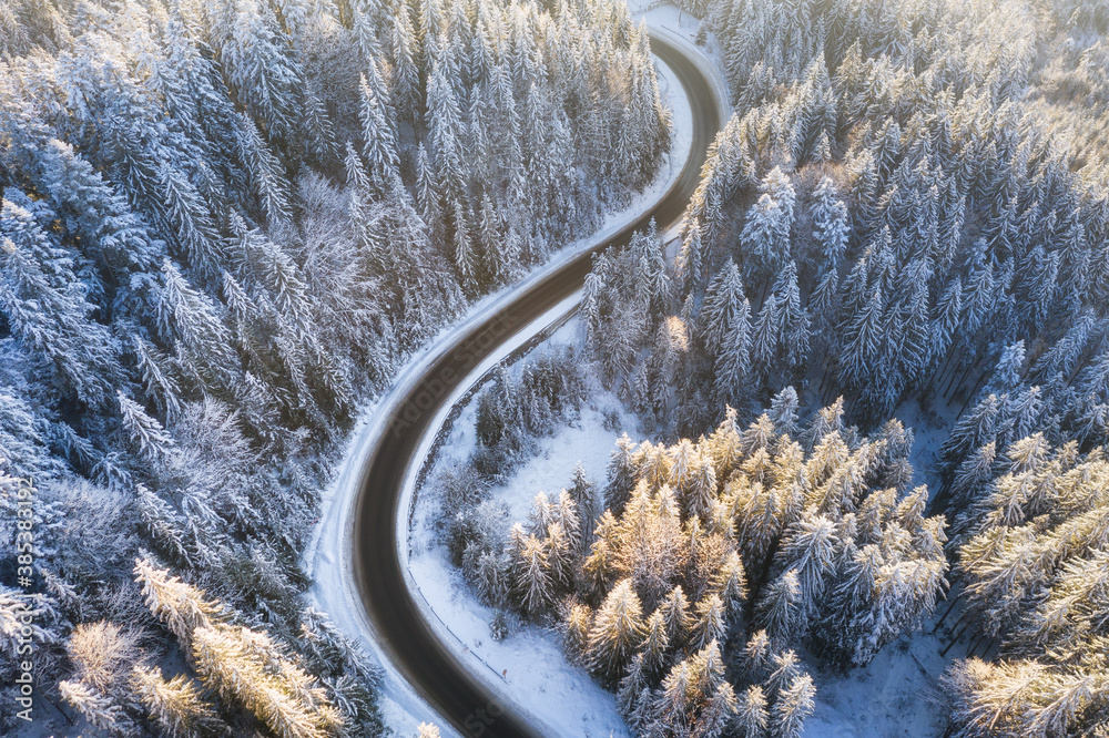 Winter chill. Natural winter landscape from air. Aerial view on the road and forest at the winter ti