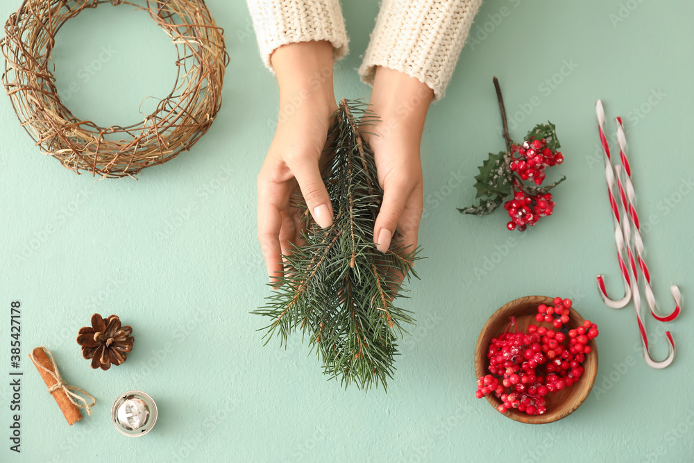 Woman making beautiful Christmas wreath on table