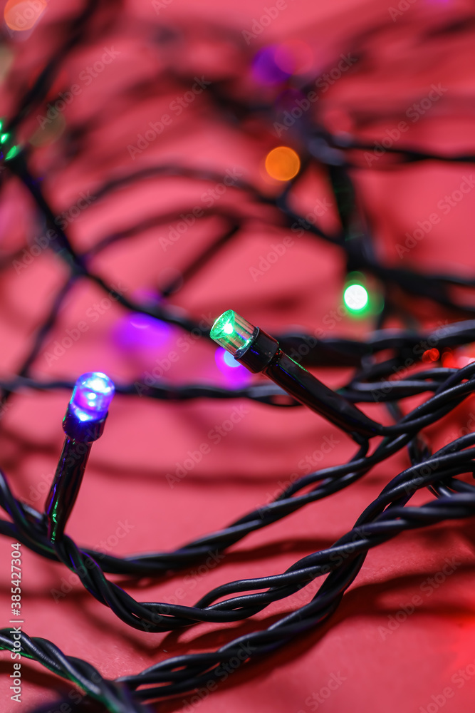 Glowing Christmas lights on color background