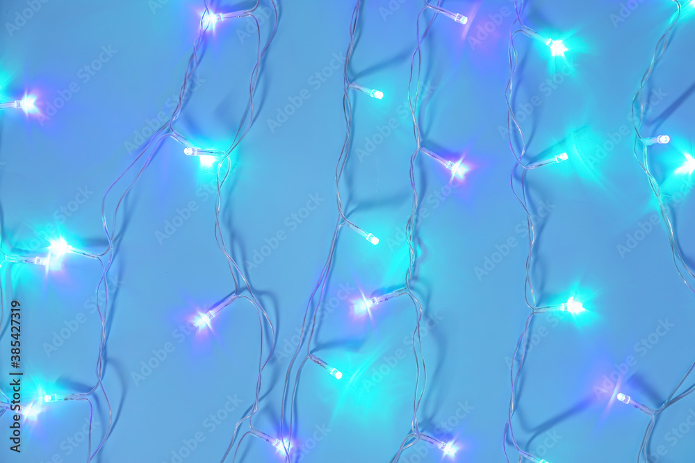 Glowing Christmas lights on color background