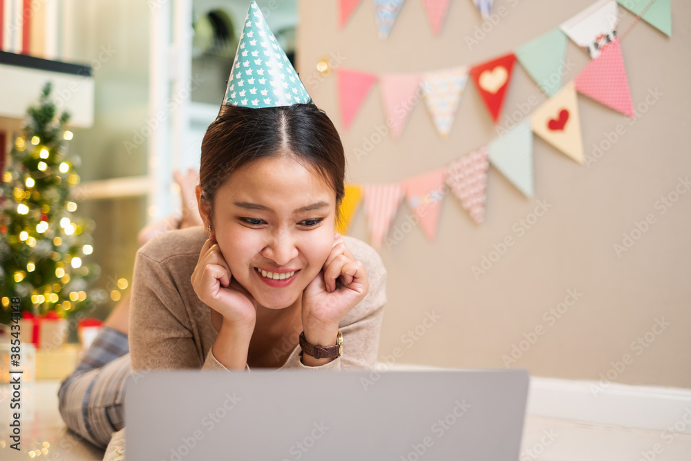 Happy Asian woman laying on floor at home using computer laptop for shopping, video call conference 