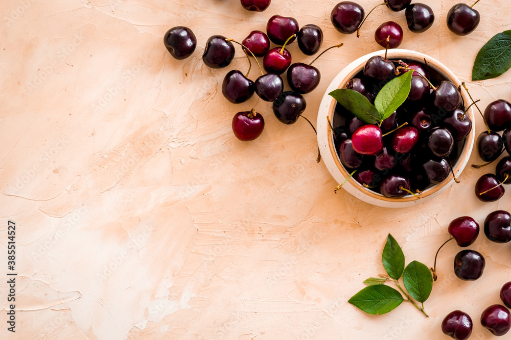 Red cherries with leaves in wooden bowl. Layout, berries background