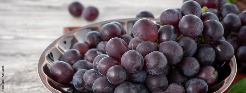 Close up of bunch of grapes fruit over wooden table background.