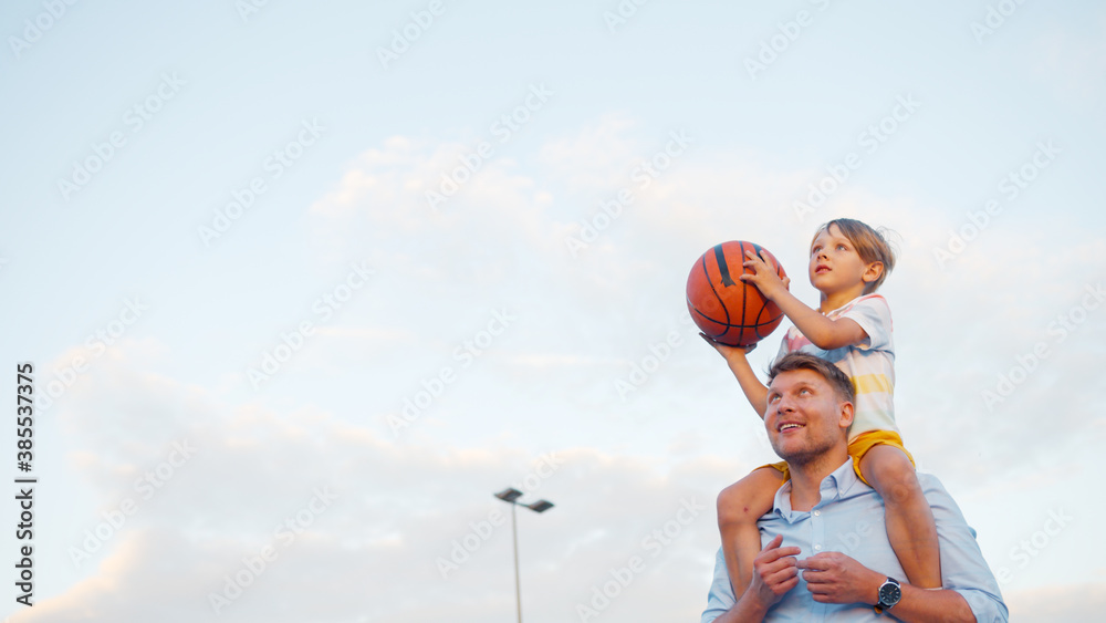 Smiling father and son playing basketball