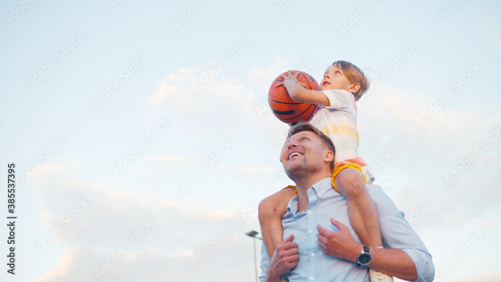 Smiling man and boy playing basketball outdoors