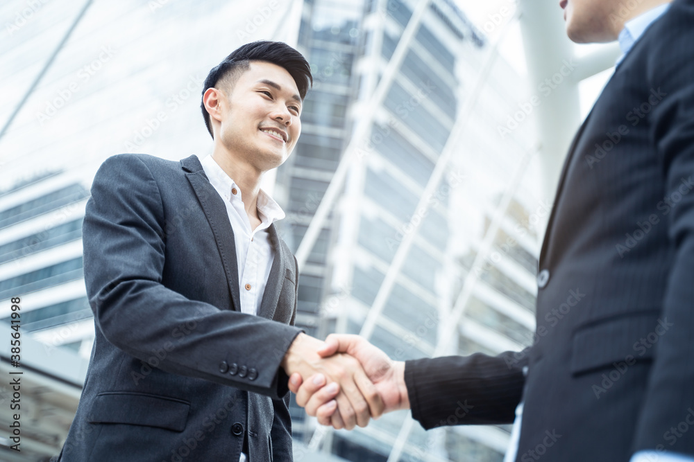 Asian businessmen make handshake in the city with building background.