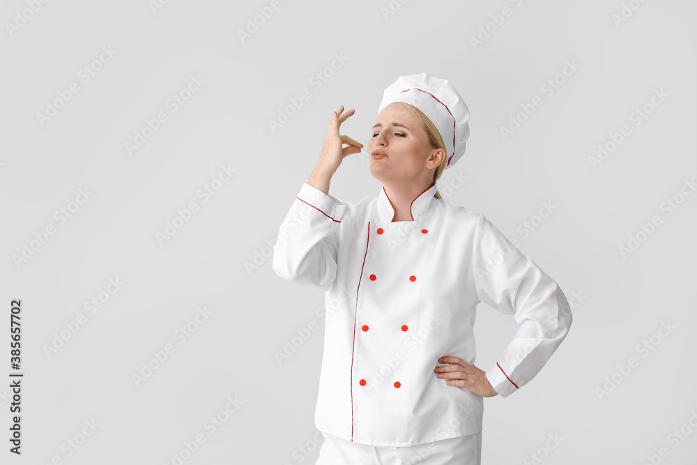 Mature female chef on grey background