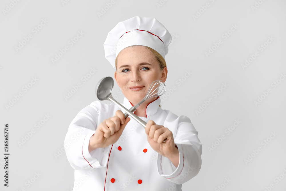 Mature female chef on grey background