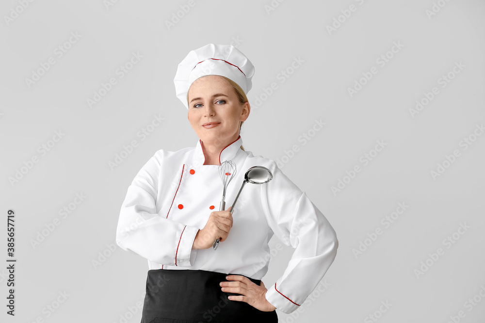 Mature female chef on grey background