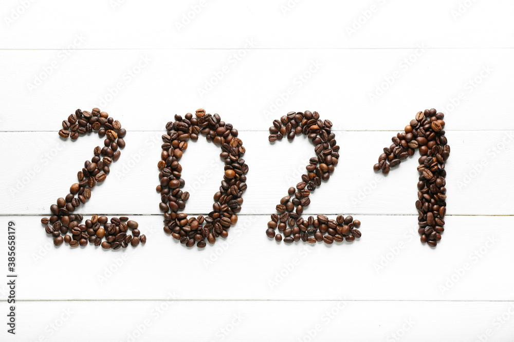 Figure 2021 made of coffee beans on white wooden background