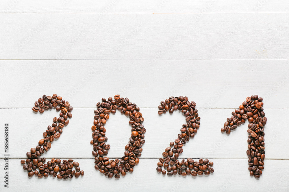 Figure 2021 made of coffee beans on white wooden background