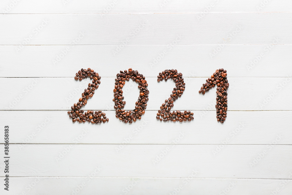 Figure 2021 made of coffee beans on white wooden background